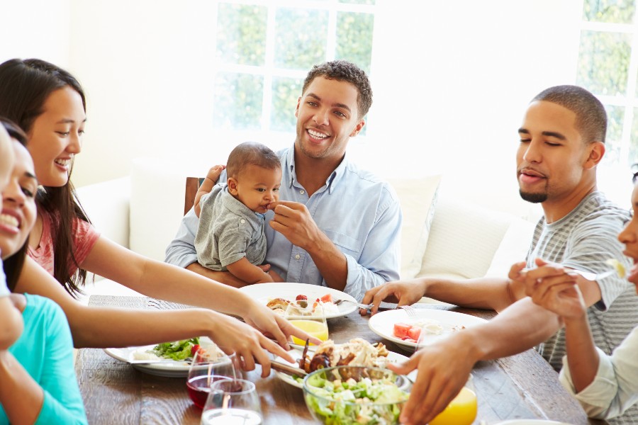 família com duas mulheres, dois homens e duas crianças ao redor da mesa no almoço de páscoa